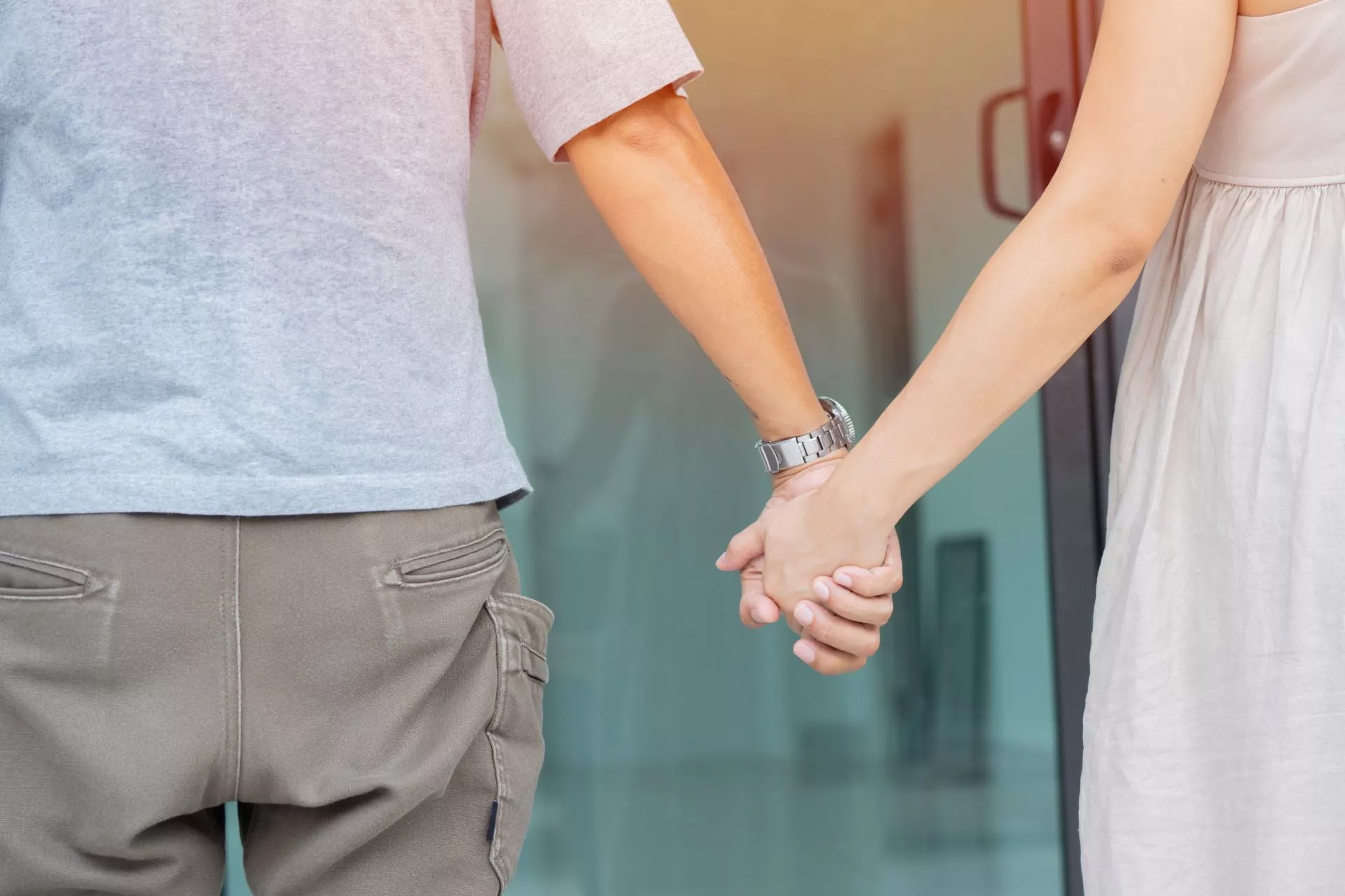 兩名使用者在戶外或建築入口前牽著手站立，畫面聚焦於手部動作，呈現同行與互動的情境。